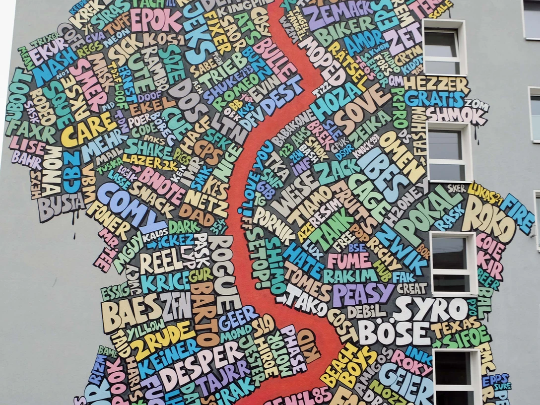 Mural Eine bunte Wandgemälde-Collage in Köln: Wörter als Kunst formen eine regionale Karte.A colorful mural collage in Cologne: words as art form a regional map.