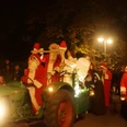 Weihnachtsmarkt 9.JPG Der Weihnachtsmann und zwei Begleiter auf einem Traktor, umgeben von Menschen bei Nacht.
