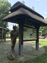Das Dorf Teufelsmoor Infotafel mit Reetdach und einer Holzskultur eines Teufels