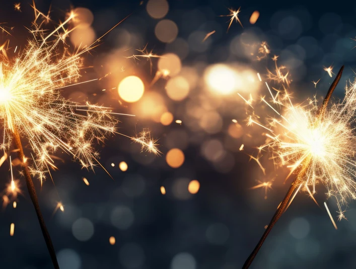 Silvester Party Zwei brennende Wunderkerzen vor verschwommenem Hintergrund aus funkelnden Lichtern in Dunkelheit.