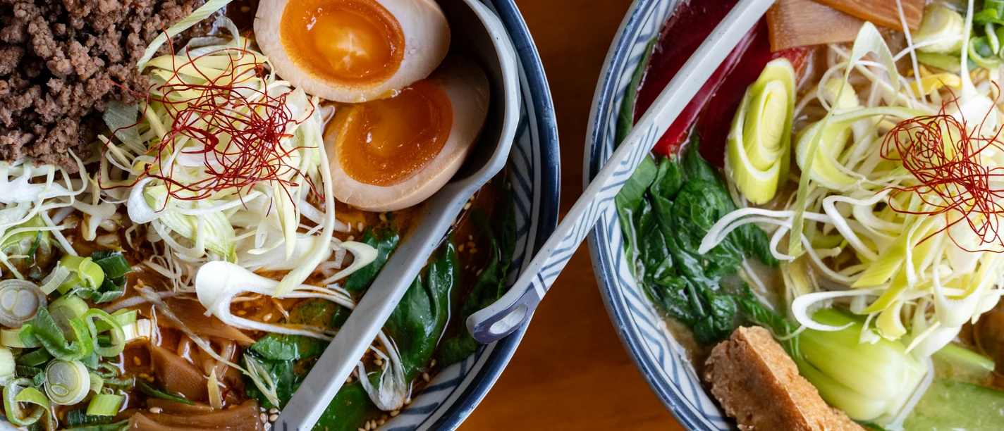 Ein Teller mit japanischen Ramen, garniert mit Eiern, Frühlingszwiebeln, gehacktem Fleisch und Gemüse.