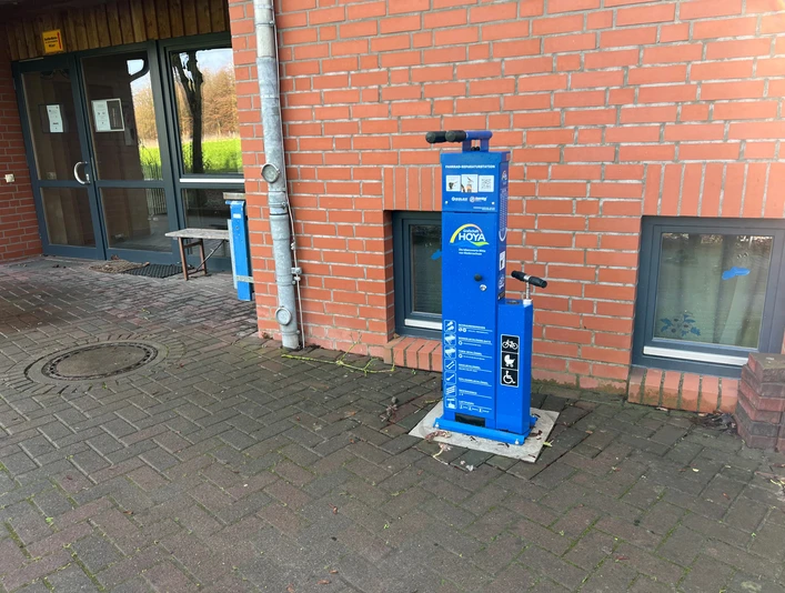 Radstation Hoyerhagen Die Radstation in Hoyerhagen bietet eine blaue Reparatursäule inklusive Luftpumpen an einer Backsteinmauer.