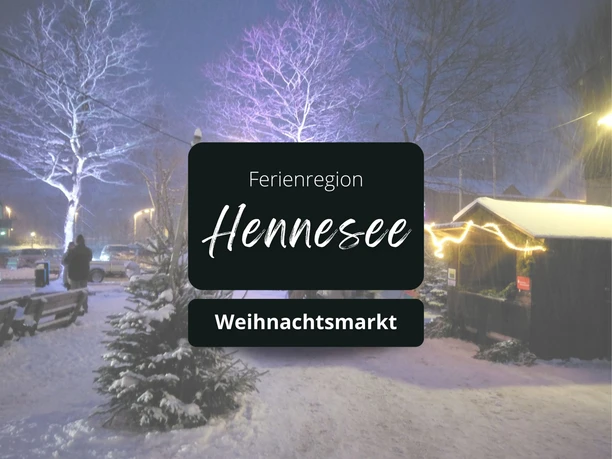 Winterlicher Weihnachtsmarkt mit beleuchtetem Stand und schneebedeckten Bäumen.