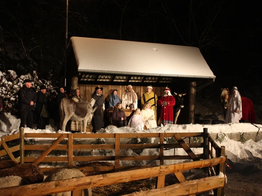 IMG_9097.JPG Eine winterliche Krippenszene im Freien mit Menschen in historischen Kostümen und einem Esel.