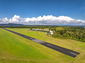 Höxter-Flugplatz Höxter-Holzminden-Teutoburger-Wald-Stadt Höxter-D-Ketz-044.jpg Luftbild der Start- und Landebahn umgeben von gemähter Wiese und Landschaft mit Flughafengebäude und Hangar rechts im Bild