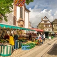 Höxter-Marktstraße-Teutoburger-Wald-Stadt Höxter-D-Ketz-005.jpg Wochenmarkt mit Gemüseständen in der Fußgängerzone mit Einkaufenden und reich verziertem Fachwerkgebäude im Hintergrund Weekly market with vegetable stalls in the pedestrian zone with shoppers and richly decorated half-timbered building in the background