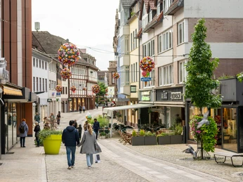 Menschen in der Fußgängerzone mit Geschäften an beiden StraßenseitenPeople in the pedestrian zone with stores on both sides of the street