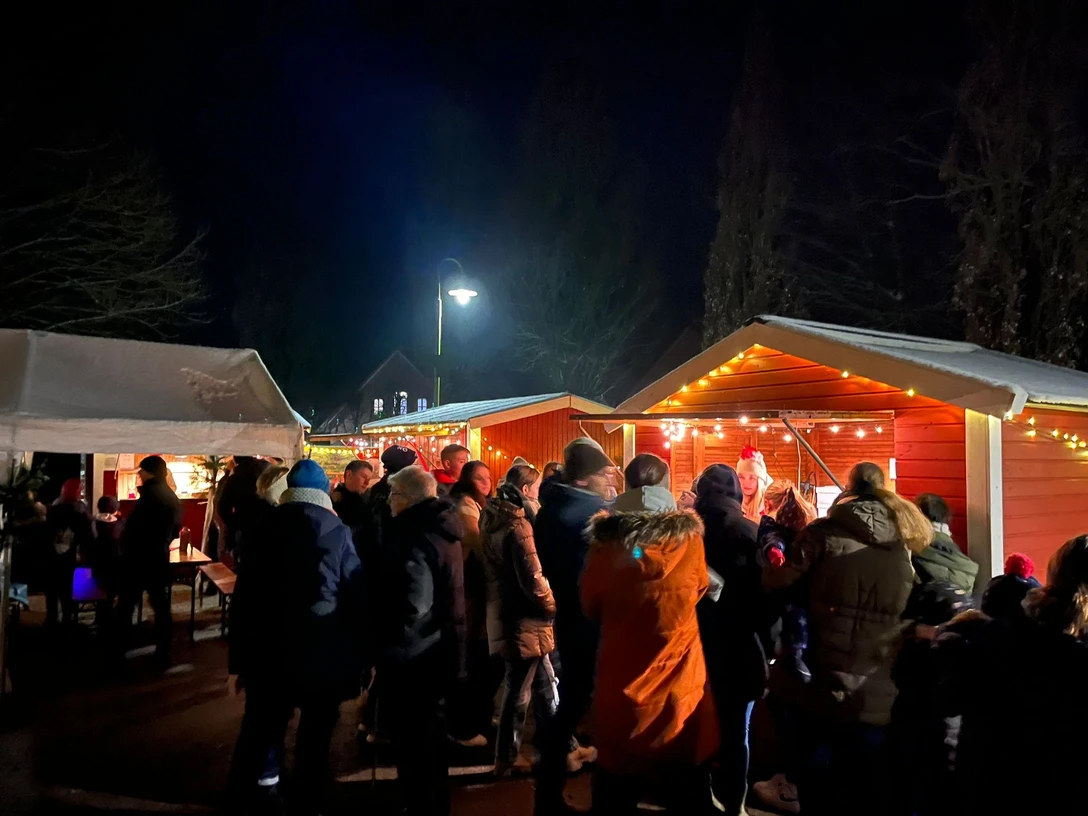 Speckendickenessen Backemoor Gruppe von Menschen in Winterkleidung vor beleuchteten Marktständen bei Nacht.