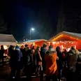 Speckendickenessen Backemoor Gruppe von Menschen in Winterkleidung vor beleuchteten Marktständen bei Nacht.