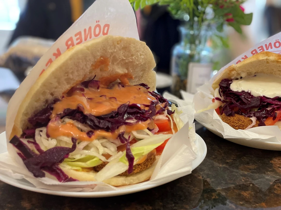Falaffel_Tasche_CCBYSA_Teutoburger Wald_Stadt_Schloß Holte-Stukenbrock.jpg Zwei gefüllte Falafeltaschen mit frischem Salat und Saucen auf weißen Tellern in einem Restaurant.