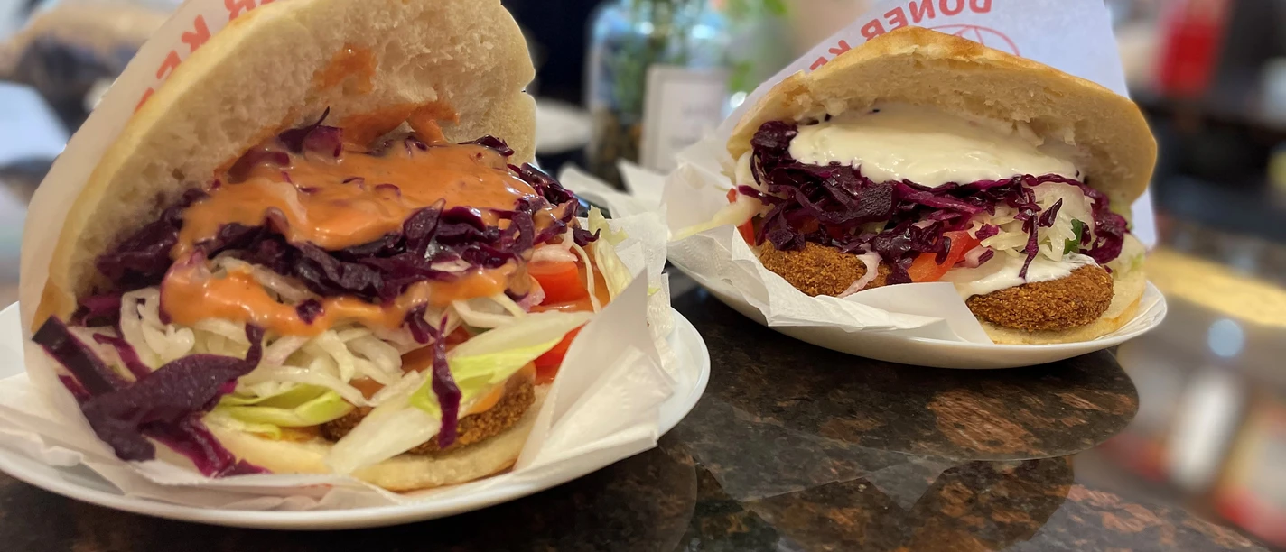 Falaffel_Tasche_CCBYSA_Teutoburger Wald_Stadt_Schloß Holte-Stukenbrock.jpg Zwei gefüllte Falafeltaschen mit frischem Salat und Saucen auf weißen Tellern in einem Restaurant.