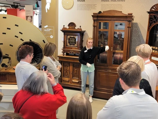 Führung Deutsches Automatenmuseum Eine Gruppe von Menschen lauscht einer Führung durch historische Musikautomaten in einem Museum.