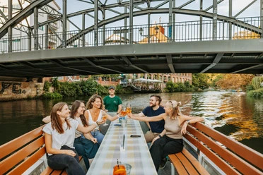Bootstour auf der Weißen Elster - Wasserstadt Leipzig Eine Gruppe fährt mit einem Boot des Stadthafens Leipzig entlang der Weißen Elster, unter der Könneritzbrücke hindurch und stößt dabei mit einem erfrischenden Cocktail an, Wasserstadt Leipzig