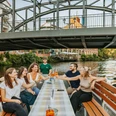 Bootstour auf der Weißen Elster - Wasserstadt Leipzig Eine Gruppe fährt mit einem Boot des Stadthafens Leipzig entlang der Weißen Elster, unter der Könneritzbrücke hindurch und stößt dabei mit einem erfrischenden Cocktail an, Wasserstadt Leipzig