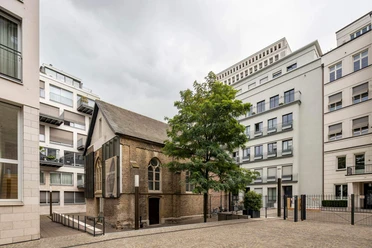 Kaune Contemporary Gallery Eine historische Kapelle, umgeben von moderner Architektur im Herzen einer Stadt.