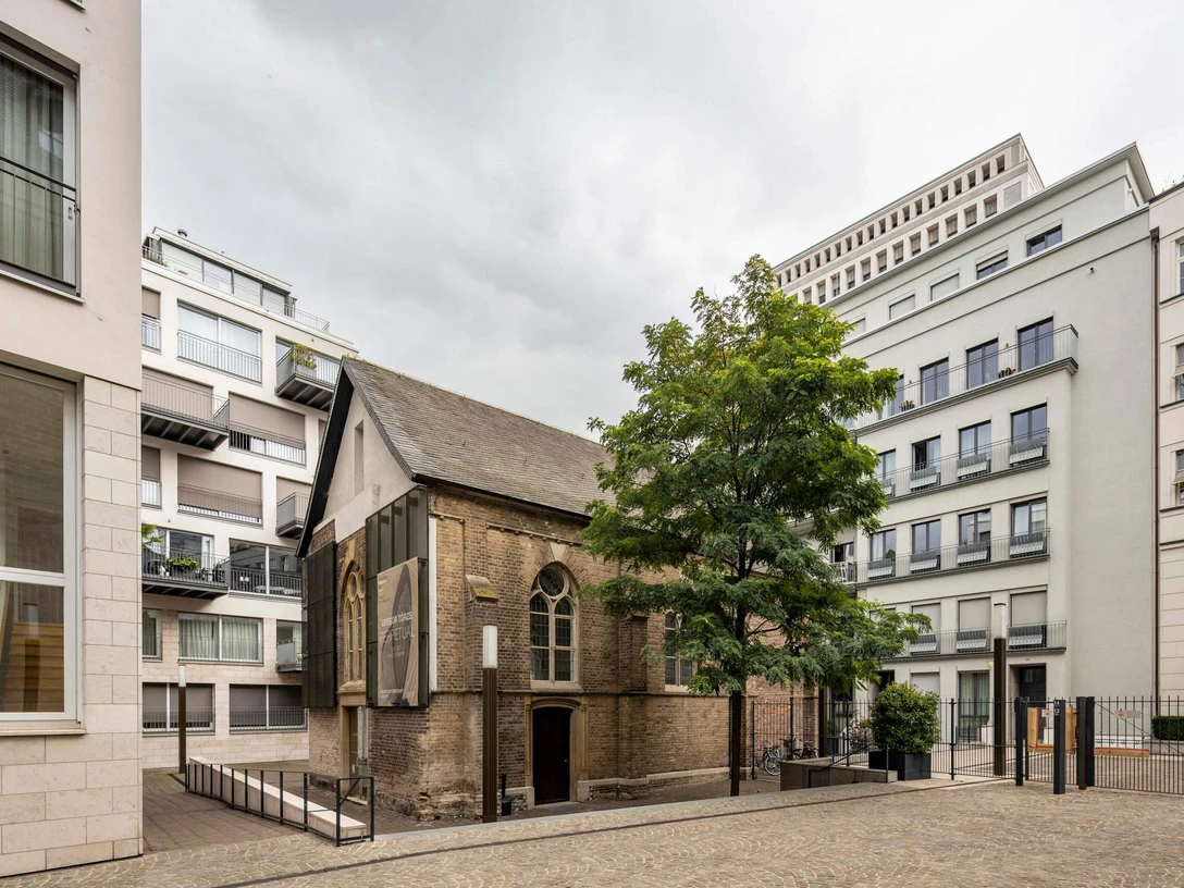 Kaune Contemporary Gallery Eine historische Kapelle, umgeben von moderner Architektur im Herzen einer Stadt.A historic chapel surrounded by modern architecture in the heart of a city.