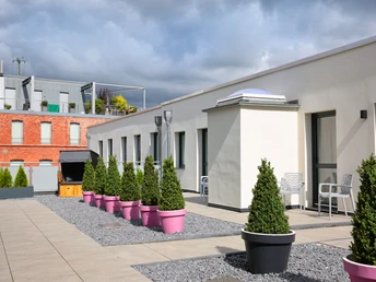 Dachterrasse mit modernen Sitzgelegenheiten und großen Pflanzkübeln; geeignet für Entspannung im Freien.
