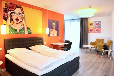 City-Hotel Apart-Go-25-Doppel.JPG Helles Doppelzimmer mit modernem Design, Kunst an den Wänden, gemütlichen Sitzmöbeln und großem Fenster.