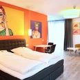 City-Hotel Apart-Go-25-Doppel.JPG Helles Doppelzimmer mit modernem Design, Kunst an den Wänden, gemütlichen Sitzmöbeln und großem Fenster.