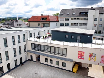 Moderner Innenhof eines Stadthotels, umgeben von mehrstöckigen Gebäuden mit teils kreativer Wandgestaltung.