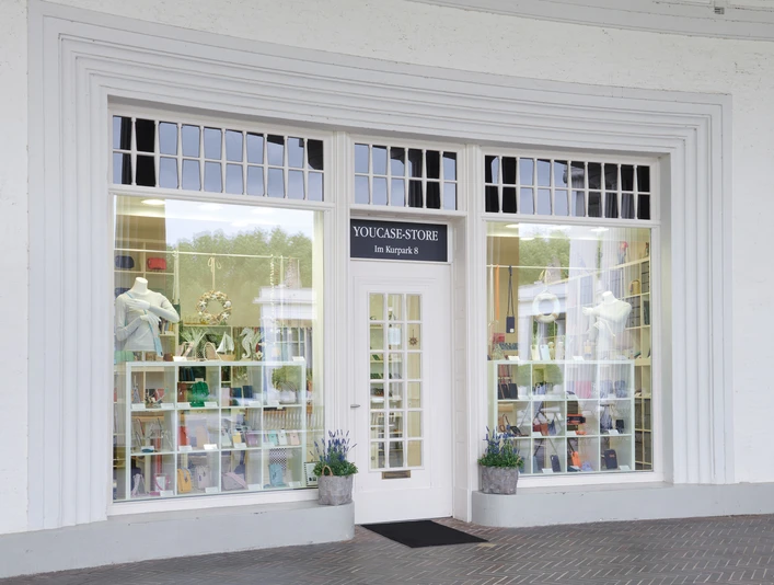 YouCaseStore Eingang eines modernen Geschäfts mit großer Fensterfront und stilvoll dekoriertem Schaufenster.