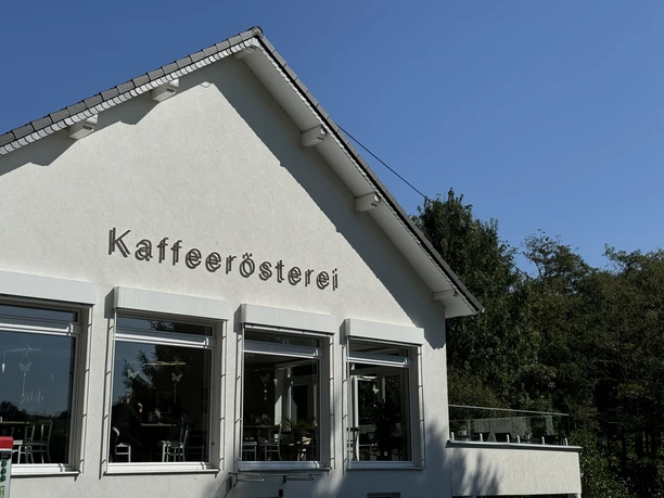 Kaffeerösterei Pagnia - Außenansicht Außenansicht einer Kaffeerösterei im modernen Gebäude mit großen Fenstern und umliegender Natur.