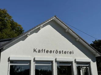 Kaffeerösterei Pagnia - Außenansicht Weiße Fassade eines Gebäudes mit dem Schriftzug "Kaffeerösterei" unter blauem Himmel.