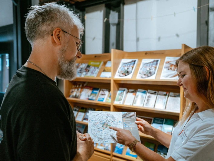 Tourist-Information Mitarbeiterin der Tourist-Information berät einen Kunden.Tourist information employee advises a customer.Turistinformationsmedarbejder rådgiver en kunde.Een medewerker van een toeristische dienst geeft advies aan een klant.