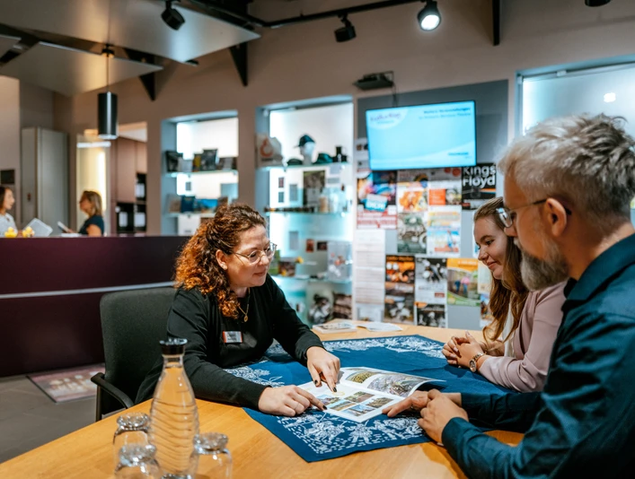 Beratung durch eine Mitarbeiterin in der Tourist-Information Advice from a member of staff at the tourist information office Rådgivning fra et medlem af personalet på turistinformationscentret Advies van een medewerker van het toeristeninformatiecentrum