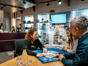 Tourist-Information Beratung durch eine Mitarbeiterin in der Tourist-Information Advice from a member of staff at the tourist information office Rådgivning fra et medlem af personalet på turistinformationscentret Advies van een medewerker van het toeristeninformatiecentrum