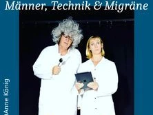 Zwei Personen in weißen Laborkitteln; eine trägt eine verrückte graue Perücke, die andere hält ein Tablet.