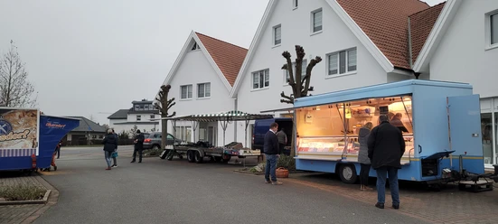 Stände auf dem Wochenmarkt Stemwede, Anbieter in blauen Verkaufswagen, Besucher bummeln entspannt.