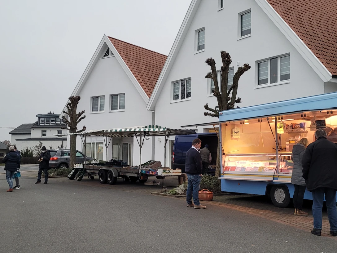 Stände auf dem Wochenmarkt Stemwede, Anbieter in blauen Verkaufswagen, Besucher bummeln entspannt.