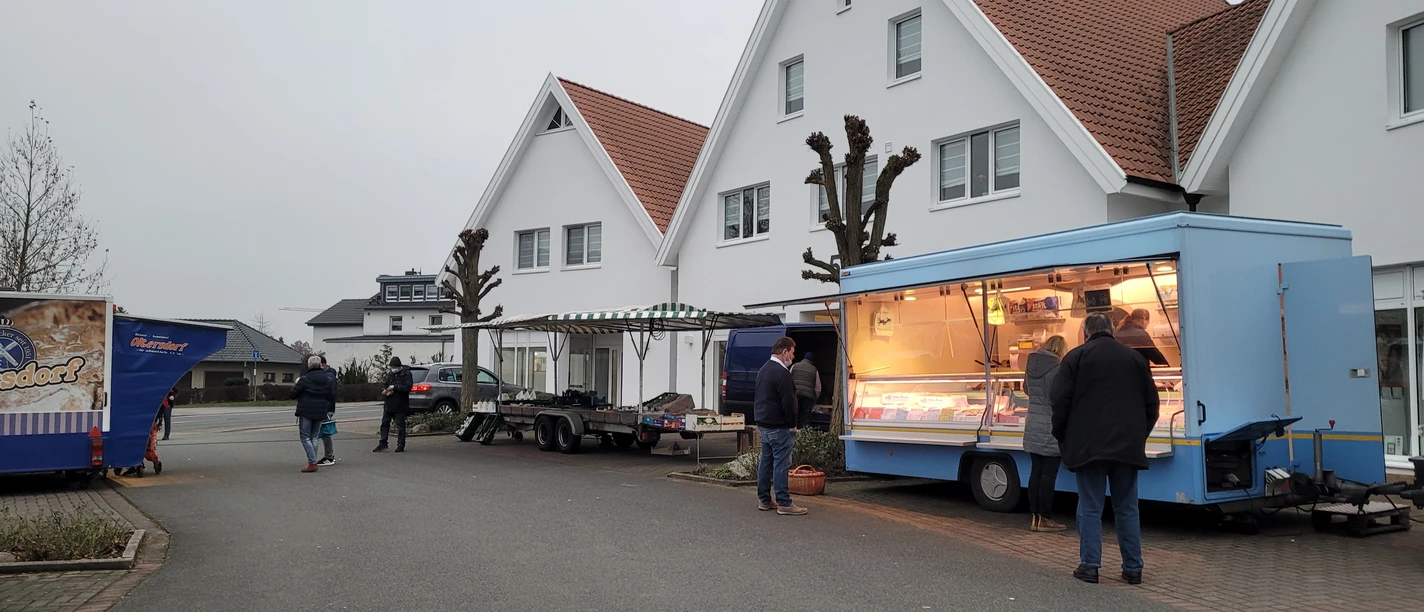 Wochenmarkt Stemwede Stände auf dem Wochenmarkt Stemwede, Anbieter in blauen Verkaufswagen, Besucher bummeln entspannt.