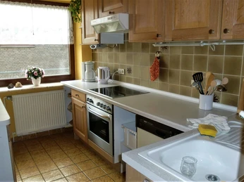 FeWo-Koetter-Kueche.jpg Geräumige Küche mit Holzschränken, moderner Ausstattung und heller Beleuchtung durch großes Fenster.