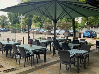 Außenbereich der Pizzeria Don Calzone in Hövelhof, mit grüner Markise und karierten Tischdecken.