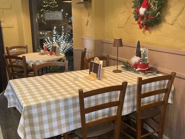 Ein festlich dekorierter Tisch in einer Pizzeria mit kariertem Tischtuch und Holzmöbeln.