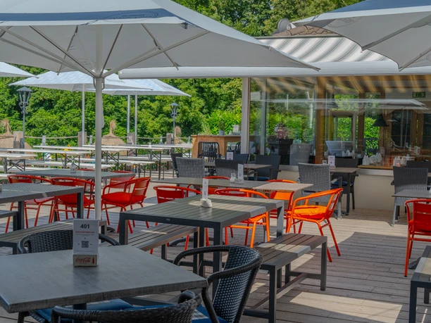 Terrasse Terrasse mit Holzboden, Esstischen, aufgespannten Schirmen und Blick ins Grüne.