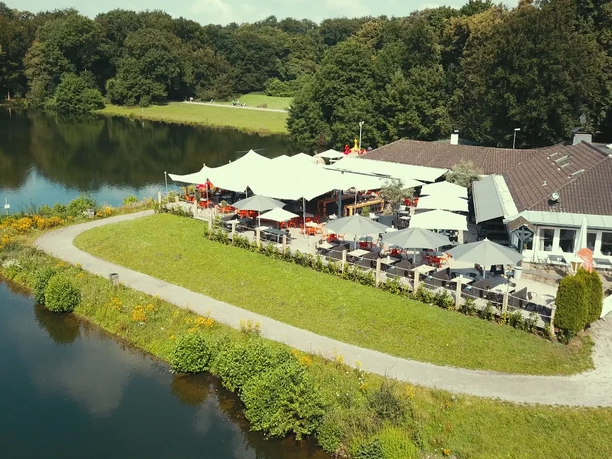 HAUS AM SEE Haus am See von oben mit Terrasse, bestückt mit aufgespannten Sonnenschirmen