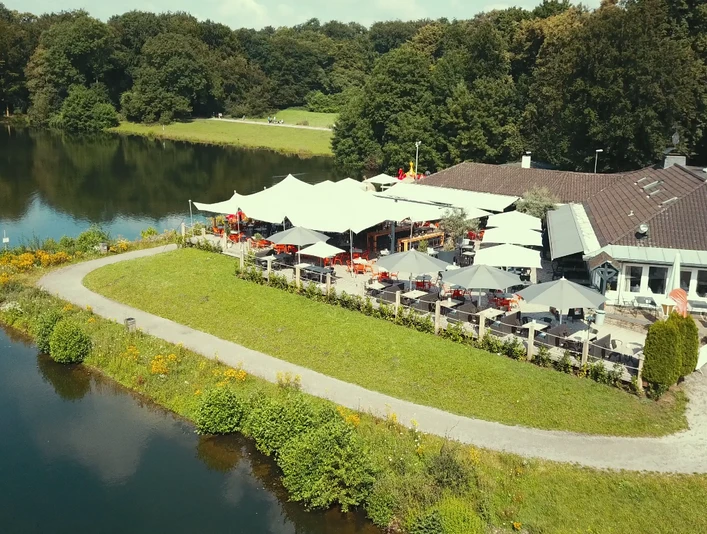 HAUS AM SEE Haus am See von oben mit Terrasse, bestückt mit aufgespannten SonnenschirmenHouse on the lake from above with terrace, equipped with stretched parasols