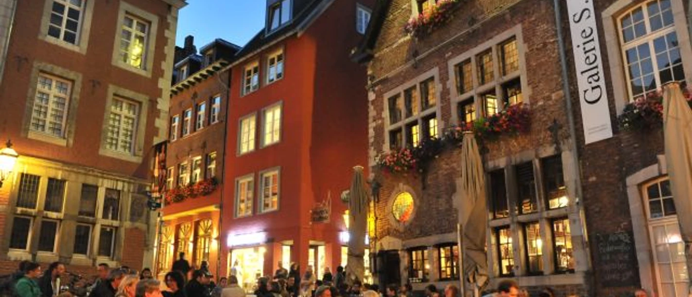 Abendbummel in Aachen Belebte Außengastronomie bei Dämmerung eingerahmt von schönen Häuserfassaden im Hof.