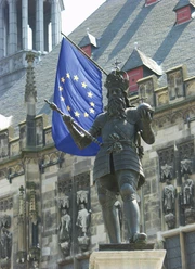 Kaiser Karl der Große in Aachen Eine Statue von Kaiser Karl dem Großen in Rüstung vor dem Aachener Rathaus und einer Europaflagge.