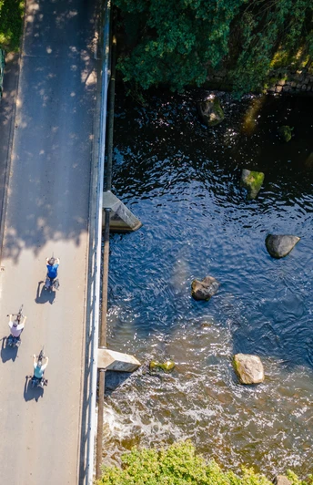 Emsbrücke bei Harsewinkel Luftaufnahme der Emsbrücke mit Radfahrern, umgeben von Bäumen und fließendem Wasser darunter.