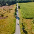 Moosheider Straße in Hövelhof Luftaufnahme einer Straße in Hövelhof, flankiert von blühender Heide und einem grünen Feld.