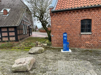 Radstation Bücken Fahrradstation neben Backsteingebäude in Bücken, umgeben von gepflastertem Boden und Natursteinen.