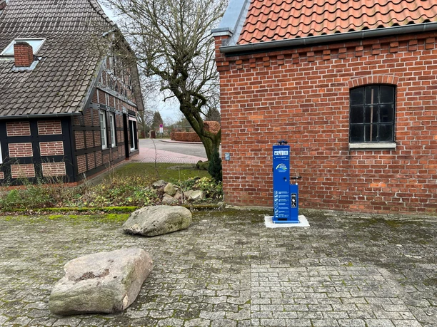 Radstation Bücken Fahrradstation neben Backsteingebäude in Bücken, umgeben von gepflastertem Boden und Natursteinen.