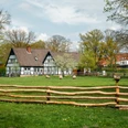 Museumshof Rahden Fachwerkgebäude mit dunklem Dach, umgeben von grüner Wiese, Bäumen und Schafen hinter Holzzaun.