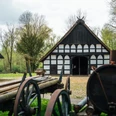 Historischer Bauernhof mit Fachwerkgebäuden und landwirtschaftlichen Maschinen im Freilichtmuseum.