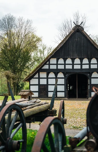 Historischer Bauernhof mit Fachwerkgebäuden und landwirtschaftlichen Maschinen im Freilichtmuseum.