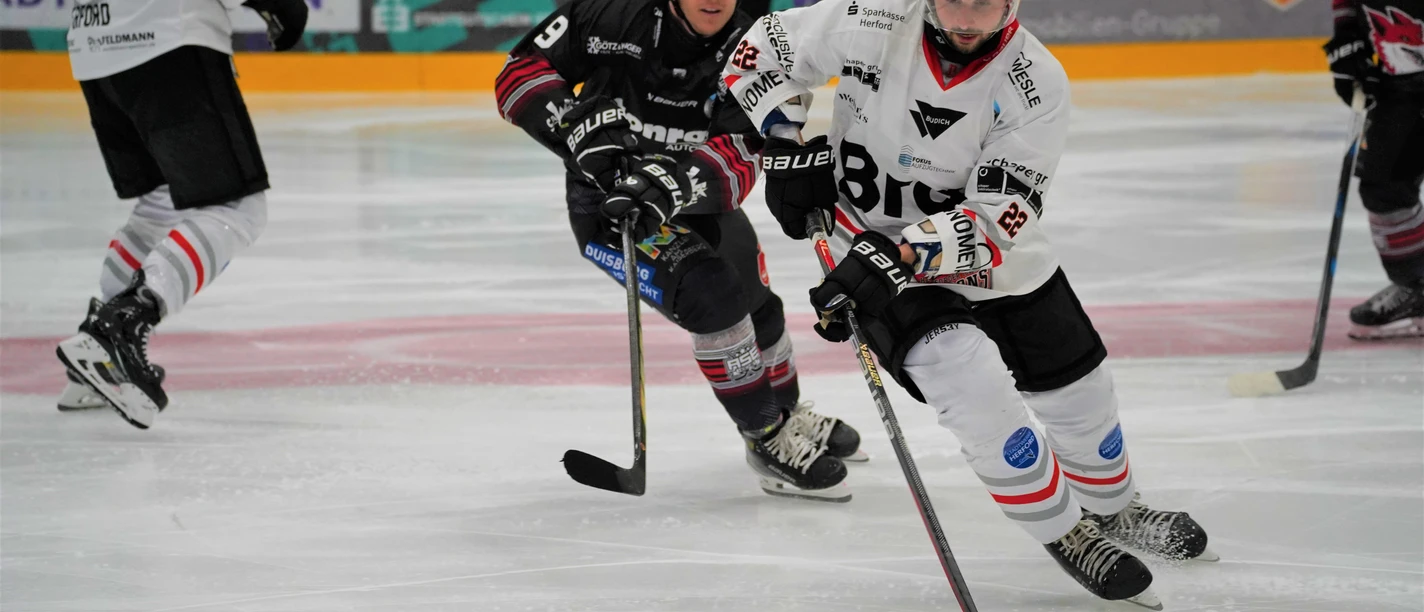 Herford-Ice-Dragons-Spiel- 4-Jana-Hemmelmann.jpg Zwei Eishockeyspieler in Bewegung, vertieft im Spielgeschehen auf einer Eisfläche während eines Matches.
